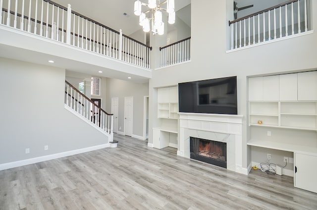 unfurnished living room featuring a towering ceiling, a fireplace, and light hardwood / wood-style floors