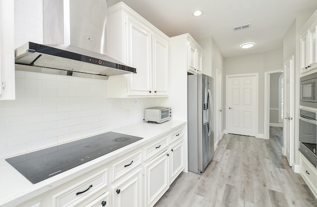 kitchen with white cabinetry, wall chimney range hood, appliances with stainless steel finishes, and light wood-type flooring