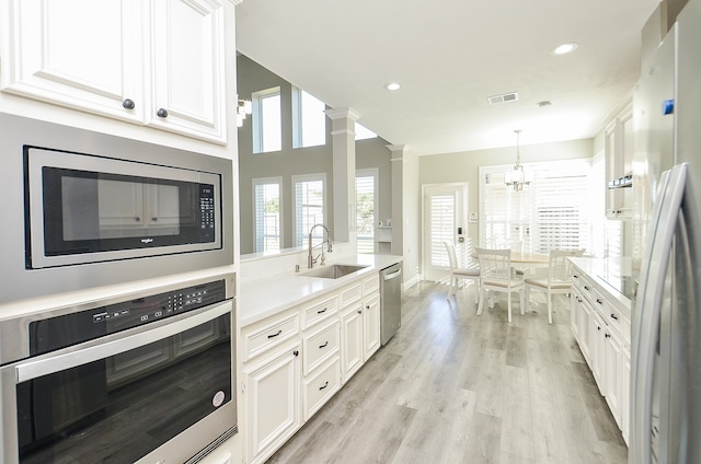 kitchen featuring white cabinetry, ornate columns, light hardwood / wood-style flooring, and appliances with stainless steel finishes