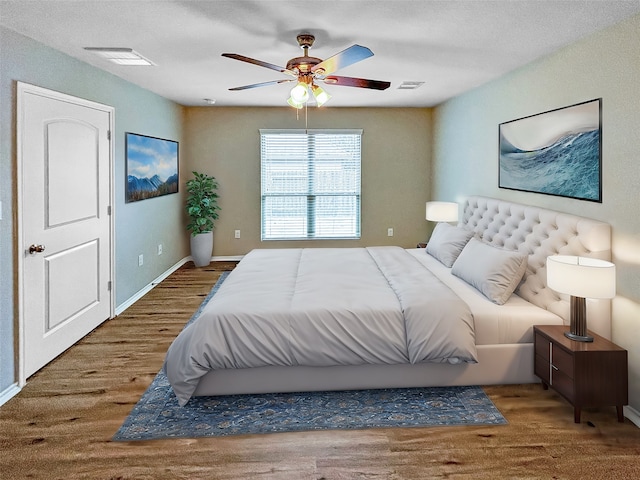 bedroom featuring hardwood / wood-style floors, a textured ceiling, and ceiling fan