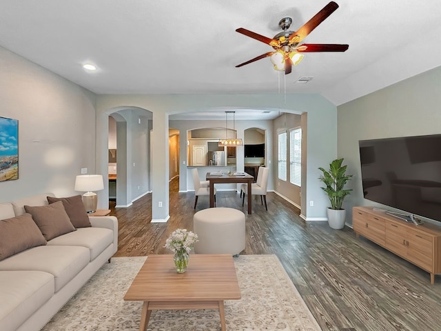 living room with dark wood-type flooring, vaulted ceiling, and ceiling fan with notable chandelier