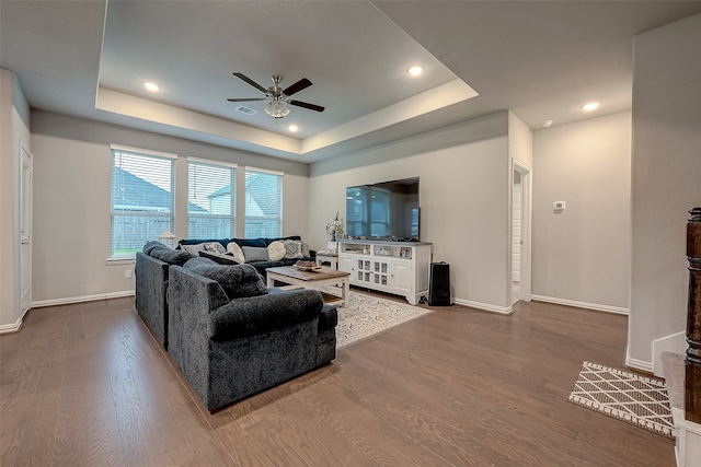 living room featuring hardwood / wood-style flooring, ceiling fan, and a tray ceiling