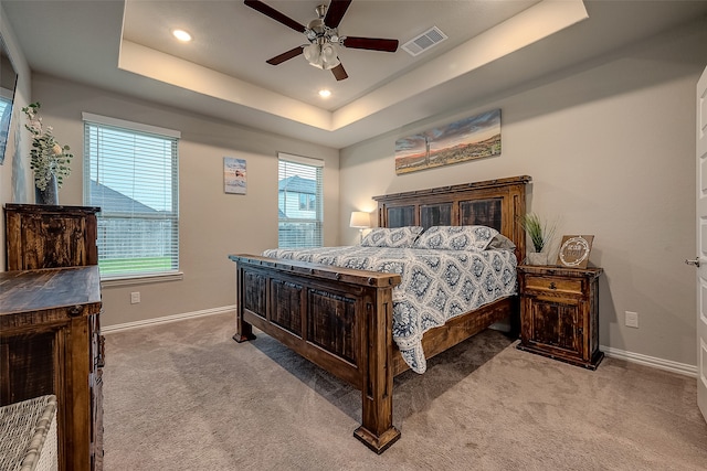 bedroom with a tray ceiling, ceiling fan, and light colored carpet