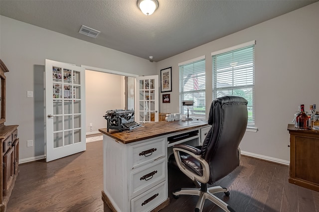 home office with a textured ceiling, dark hardwood / wood-style flooring, and french doors