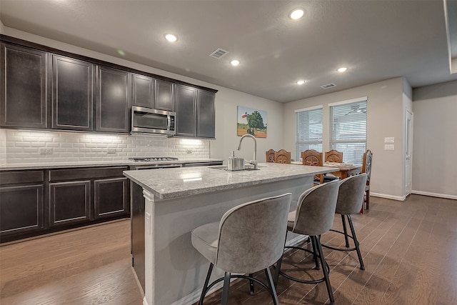 kitchen featuring a kitchen bar, sink, an island with sink, and hardwood / wood-style flooring