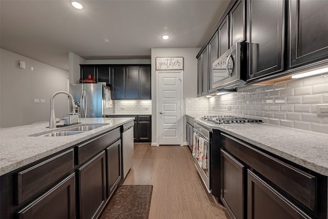 kitchen with hardwood / wood-style flooring, decorative backsplash, sink, and appliances with stainless steel finishes