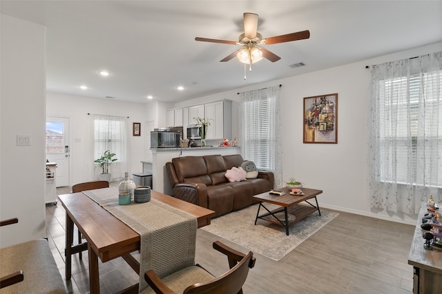 living room featuring light hardwood / wood-style floors, a healthy amount of sunlight, and ceiling fan