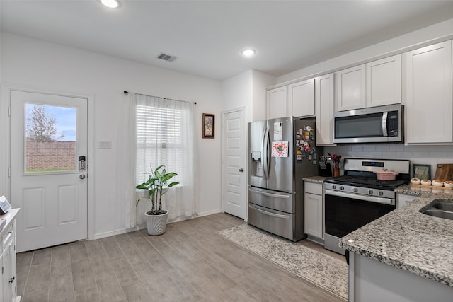 kitchen featuring light hardwood / wood-style floors, white cabinetry, light stone countertops, and stainless steel appliances