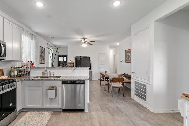 kitchen with white cabinets, stainless steel appliances, sink, and light wood-type flooring