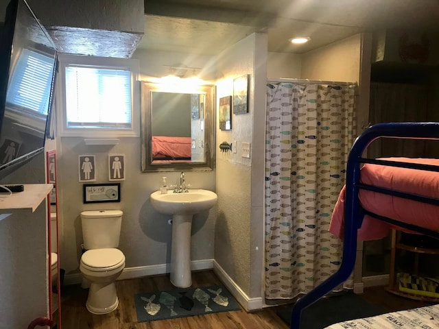 bathroom featuring toilet, wood-type flooring, and walk in shower