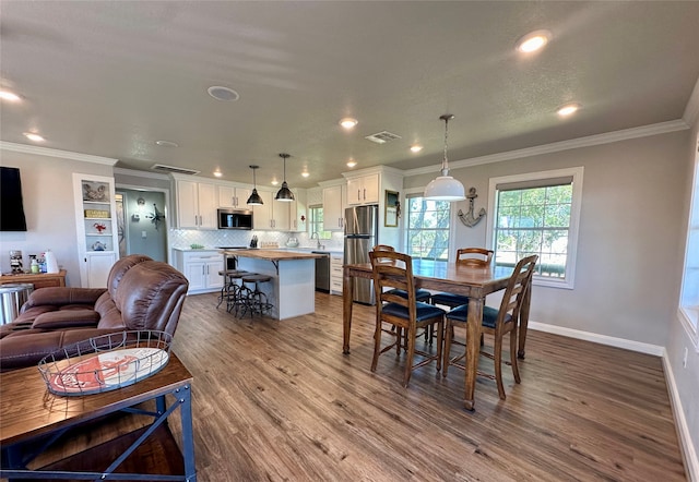 dining space with hardwood / wood-style flooring and crown molding