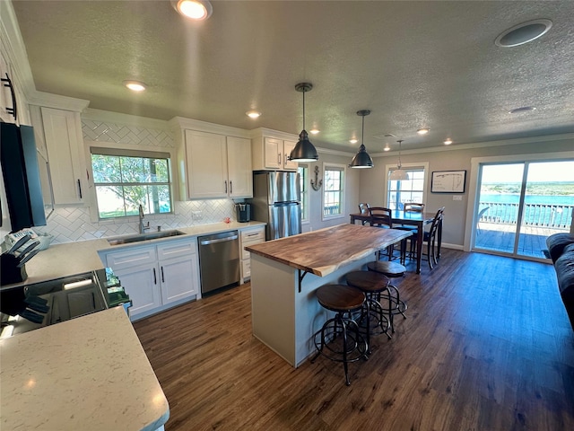 kitchen featuring white cabinetry, sink, stainless steel appliances, pendant lighting, and a kitchen island