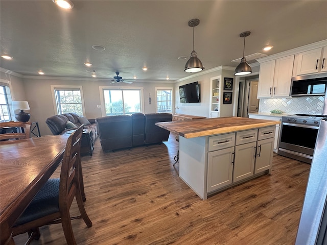 kitchen with butcher block counters, white cabinetry, pendant lighting, and stainless steel appliances