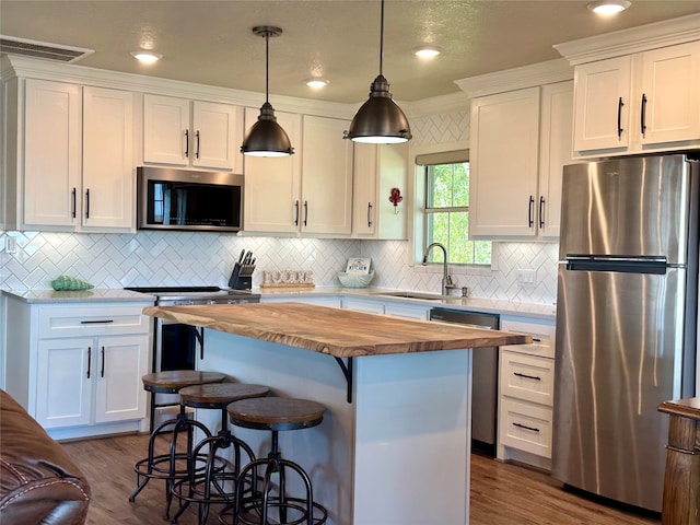 kitchen featuring white cabinets, decorative light fixtures, sink, and stainless steel appliances