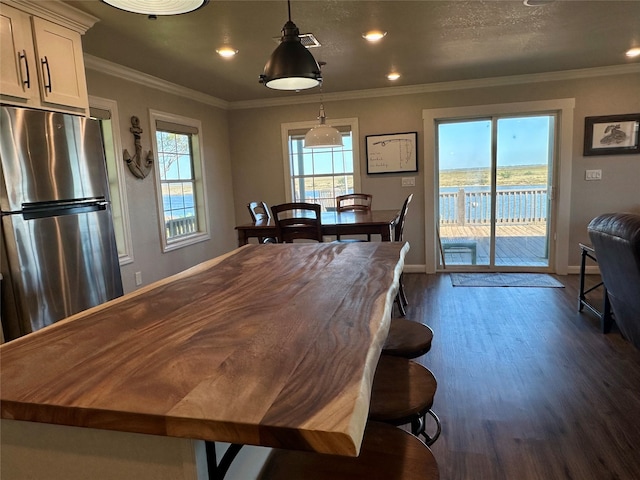 dining area with dark hardwood / wood-style flooring, ornamental molding, and a wealth of natural light