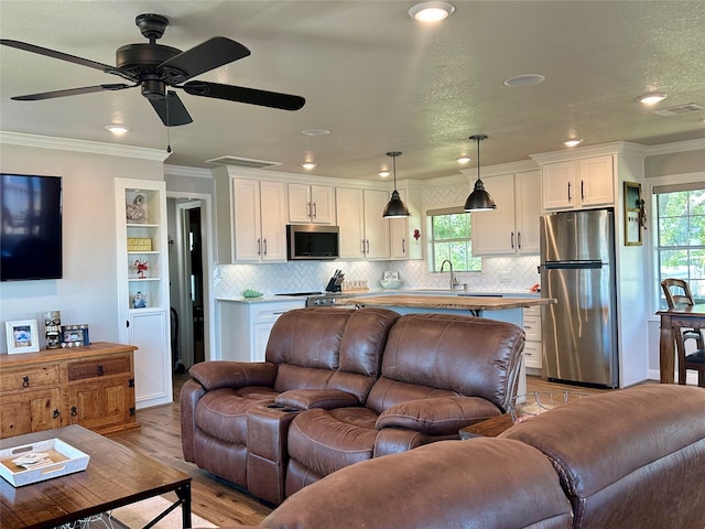 living room featuring a wealth of natural light, light hardwood / wood-style flooring, and crown molding