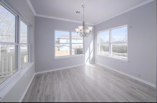 spare room featuring wood-type flooring, an inviting chandelier, plenty of natural light, and crown molding