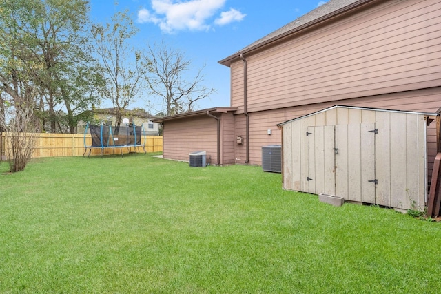 view of yard with central AC unit, a trampoline, and a storage unit