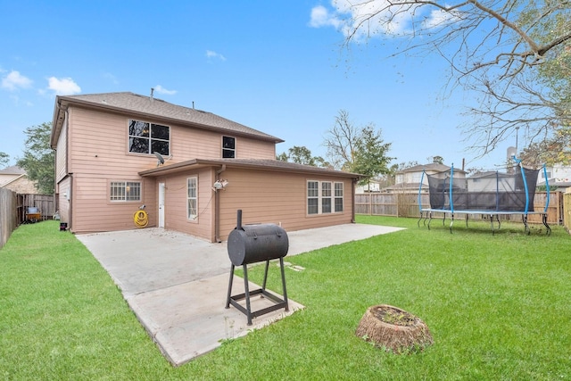 rear view of property with a lawn, a trampoline, and a patio area