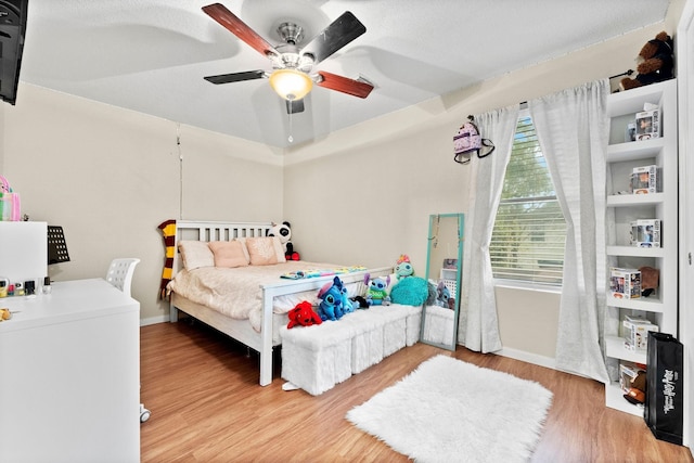 bedroom with hardwood / wood-style floors, ceiling fan, and a textured ceiling