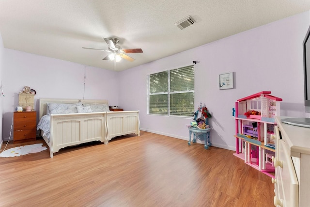 bedroom featuring light hardwood / wood-style floors, ceiling fan, and a textured ceiling