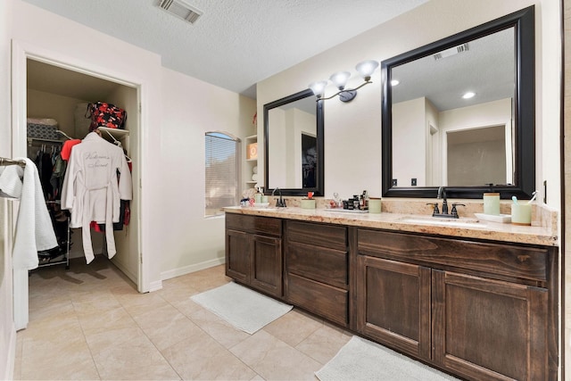 bathroom with vanity, a textured ceiling, and tile patterned floors