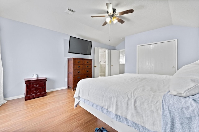 bedroom featuring ceiling fan, connected bathroom, light wood-type flooring, and vaulted ceiling