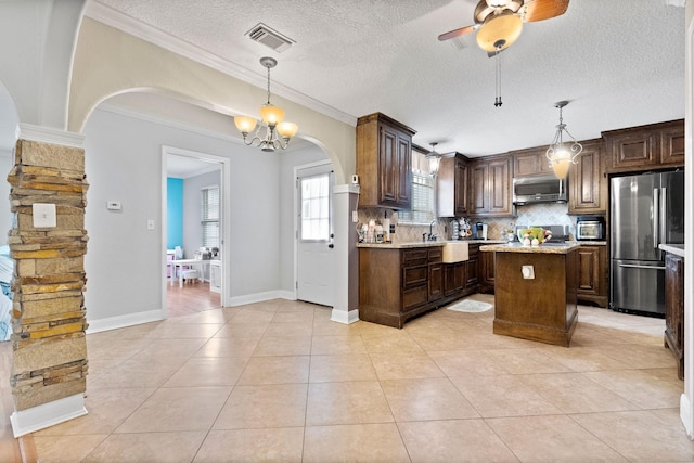 kitchen featuring appliances with stainless steel finishes, ornamental molding, backsplash, a center island, and pendant lighting