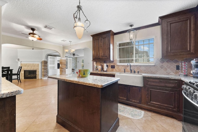 kitchen featuring sink, ceiling fan, crown molding, a kitchen island, and pendant lighting