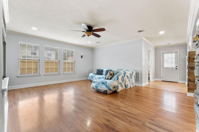 unfurnished living room featuring crown molding, a stone fireplace, a textured ceiling, ceiling fan, and light hardwood / wood-style flooring