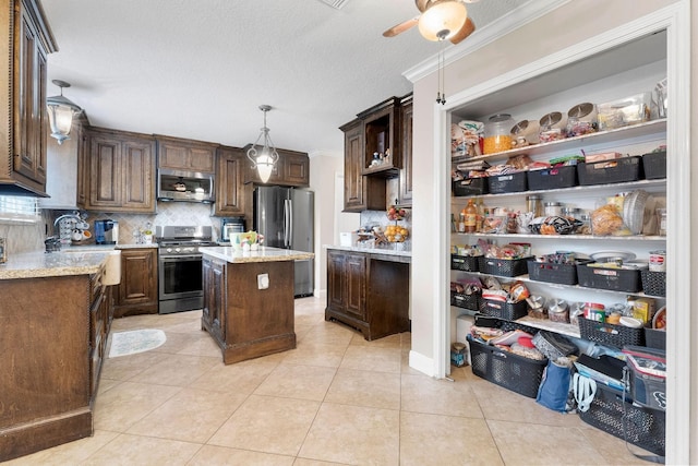 kitchen with stainless steel appliances, light tile patterned floors, backsplash, crown molding, and a center island