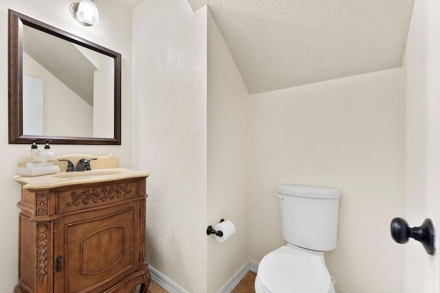 bathroom featuring vanity, toilet, a textured ceiling, and lofted ceiling