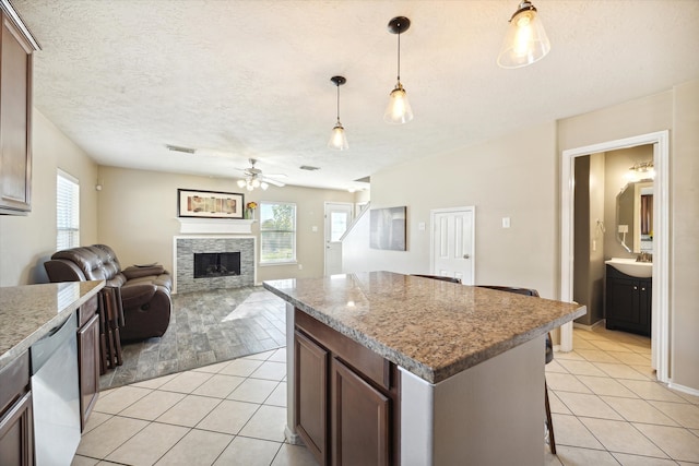 kitchen with light stone countertops, stainless steel dishwasher, a textured ceiling, ceiling fan, and decorative light fixtures