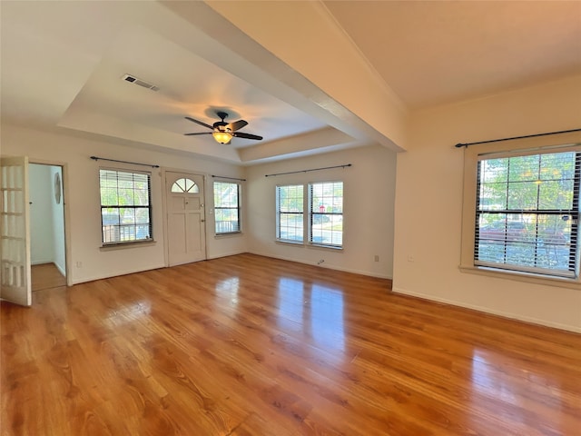 unfurnished living room with ceiling fan, light wood-type flooring, and a raised ceiling