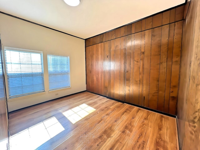 empty room featuring wood walls and light wood-type flooring