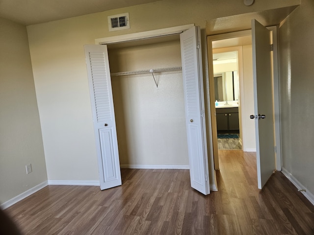 unfurnished bedroom with dark wood-type flooring, a closet, and sink