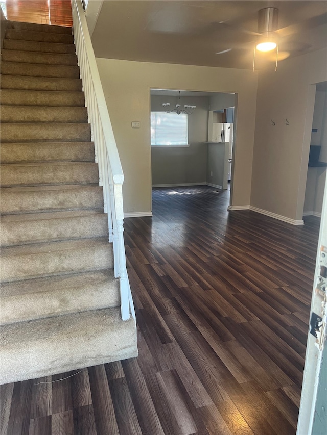 staircase with ceiling fan with notable chandelier and hardwood / wood-style floors