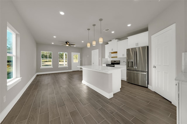 kitchen with white cabinets, dark hardwood / wood-style floors, stainless steel appliances, decorative light fixtures, and a center island