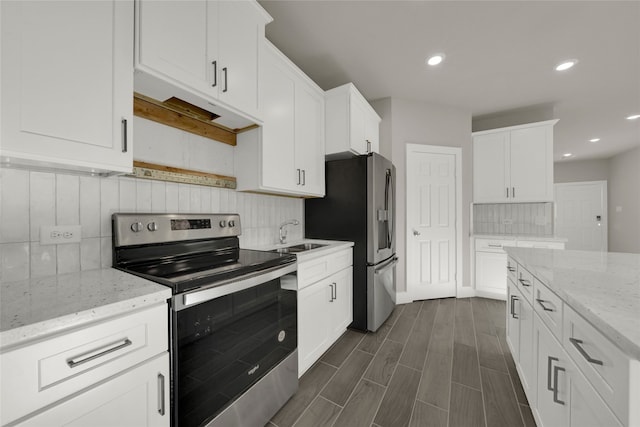 kitchen featuring dark hardwood / wood-style floors, stainless steel appliances, white cabinets, light stone counters, and tasteful backsplash