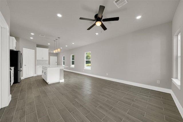 kitchen with hanging light fixtures, white cabinetry, stainless steel refrigerator, dark hardwood / wood-style floors, and a center island