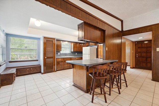 1631 Gault Rd, Houston, TX 77039 - kitchen featuring wood walls, light tile patterned floors, a kitchen bar, and freestanding refrigerator