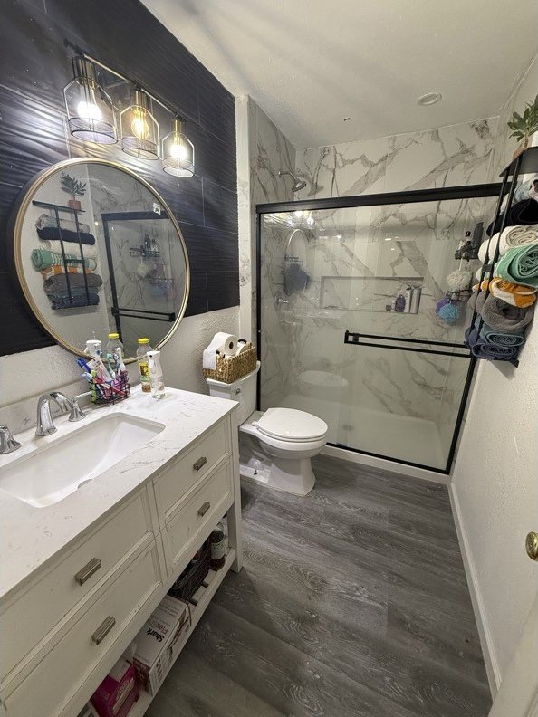 bathroom featuring vanity, an enclosed shower, hardwood / wood-style flooring, and toilet