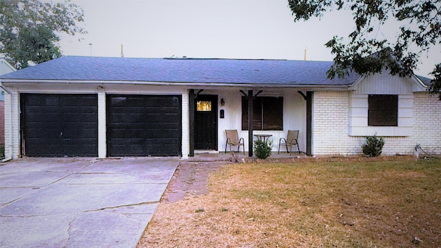 ranch-style house featuring brick siding, a porch, concrete driveway, an attached garage, and a front lawn