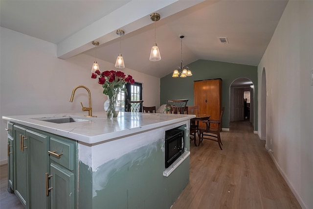 515 Cappamore St, Houston, TX 77013 - kitchen with a sink, arched walkways, black microwave, light wood finished floors, and vaulted ceiling