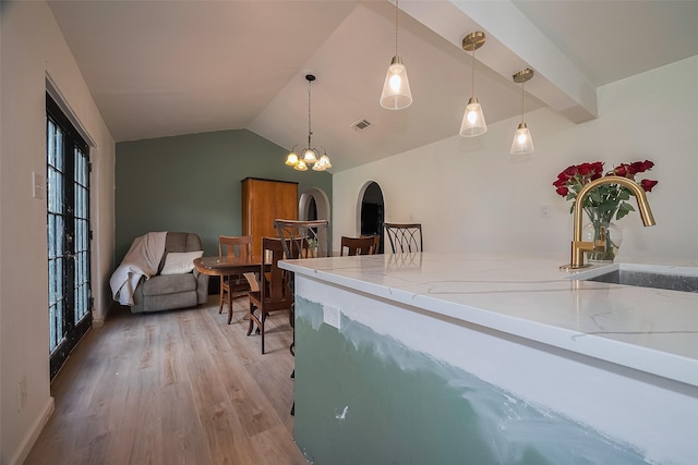 515 Cappamore St, Houston, TX 77013 - kitchen featuring light wood-style floors, a sink, vaulted ceiling, decorative light fixtures, and light stone counters