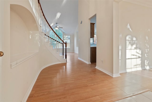 foyer with light hardwood / wood-style floors, a high ceiling, and ceiling fan