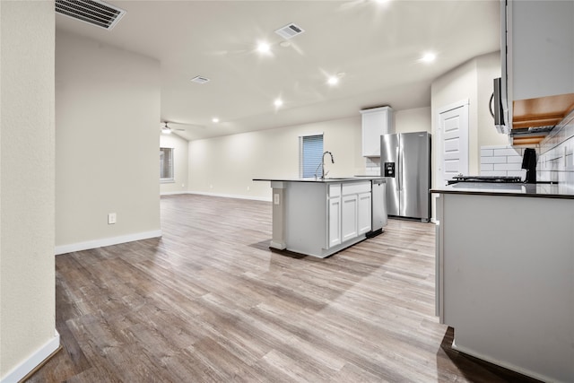 kitchen featuring a center island with sink, white cabinetry, appliances with stainless steel finishes, and light hardwood / wood-style flooring