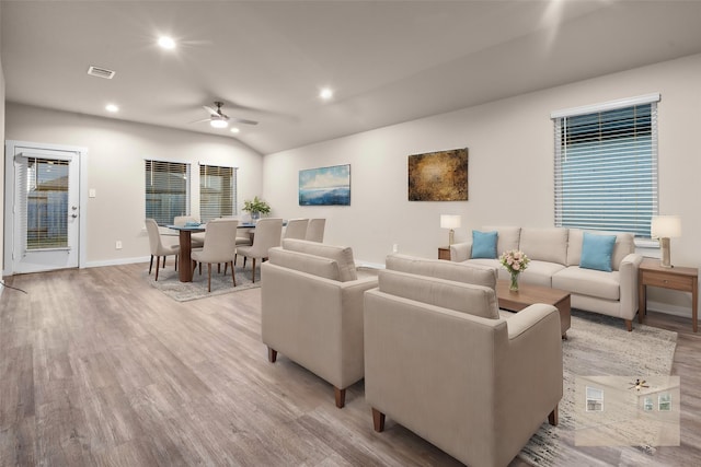 living room with ceiling fan, light hardwood / wood-style flooring, and vaulted ceiling