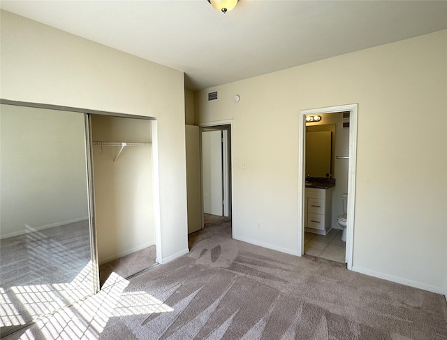 unfurnished bedroom featuring a closet, connected bathroom, and light colored carpet