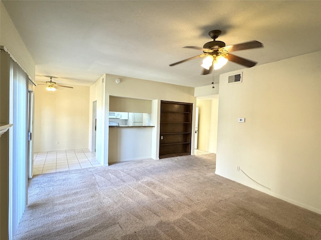 unfurnished living room with light colored carpet and ceiling fan